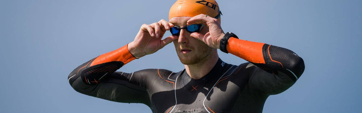 Harry Palmer, triathlète professionnel, portant la combinaison néoprène Vanquish-X, un bonnet de bain orange et des lunettes de natation Volare