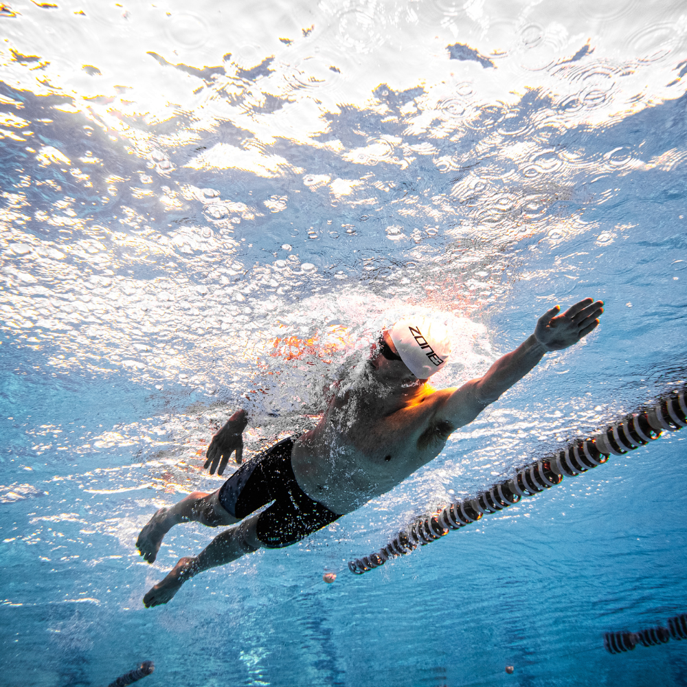 Nageur en action sous l'eau avec un bonnet de bain et des lunettes de natation.