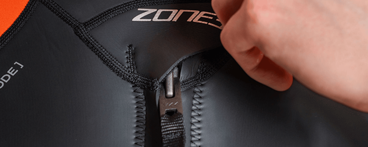 Close-up of a person adjusting a zipper on a Zone3 wetsuit.