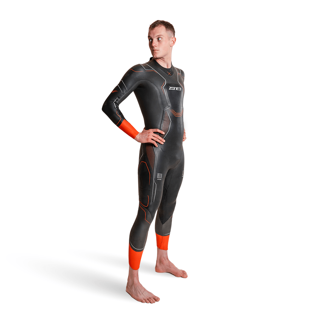Vue latérale d'un homme portant la combinaison néoprène Zone3 Vanquish-X avec touches d'orange sur fond blanc. 